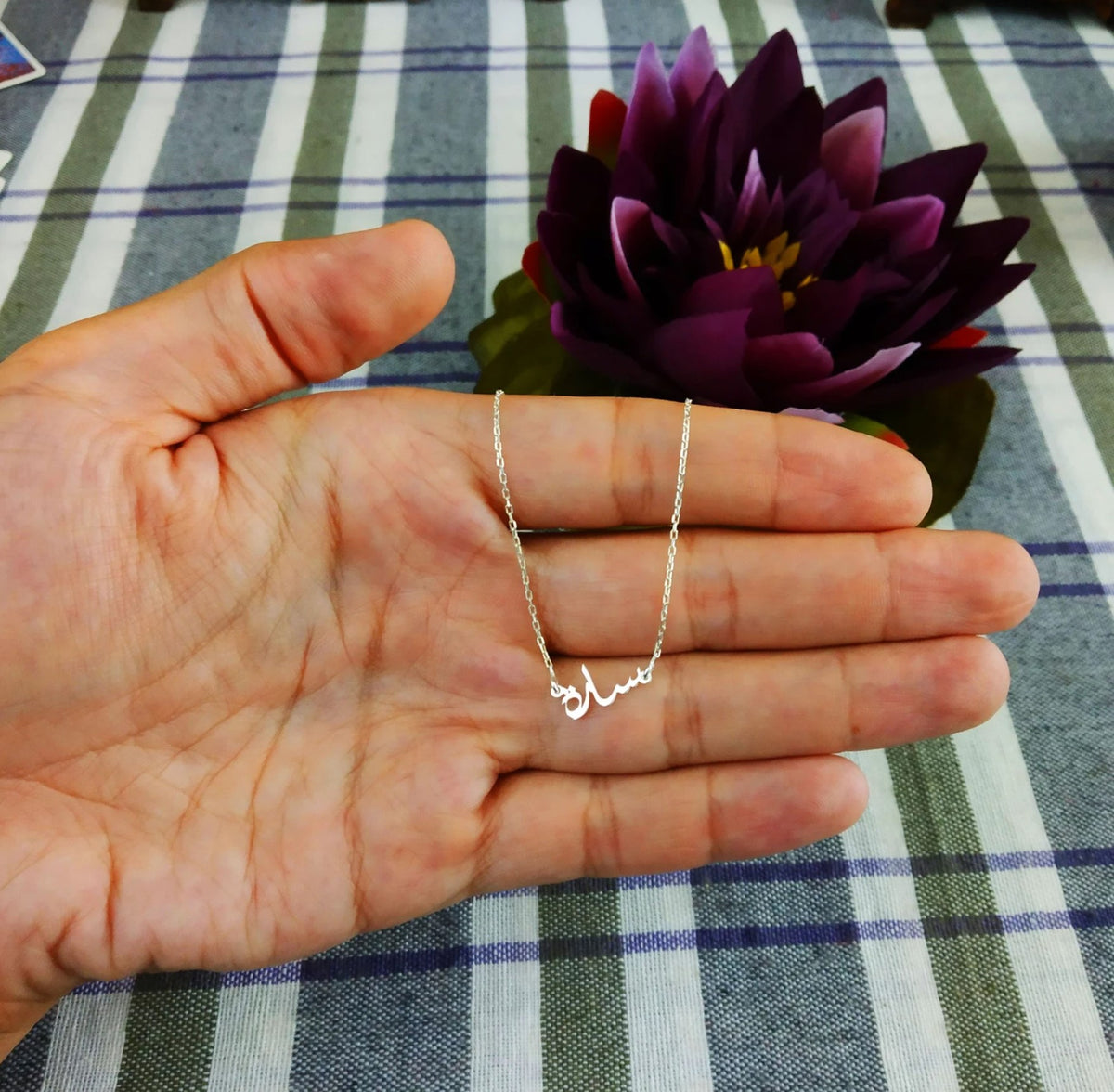 Tiny Arabic name necklace by MUHVA STORE featuring a delicate gold chain and personalized Arabic script pendant.