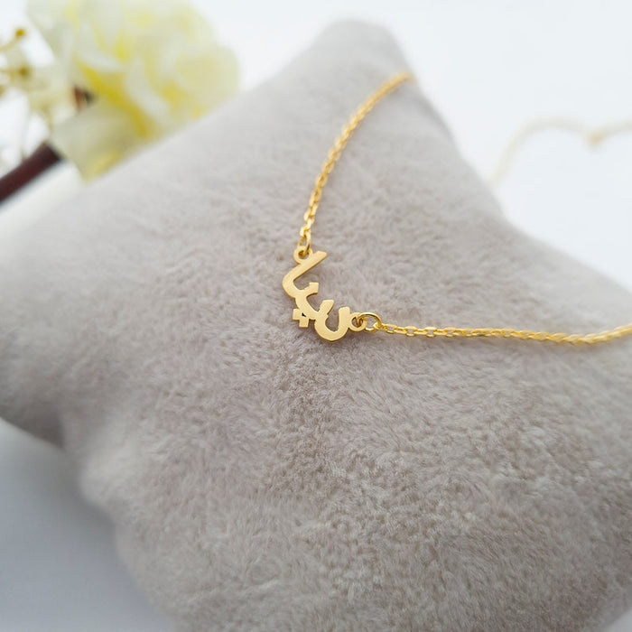 Tiny Arabic name necklace from MUHVA STORE featuring delicate gold chain and personalized Arabic script pendant.