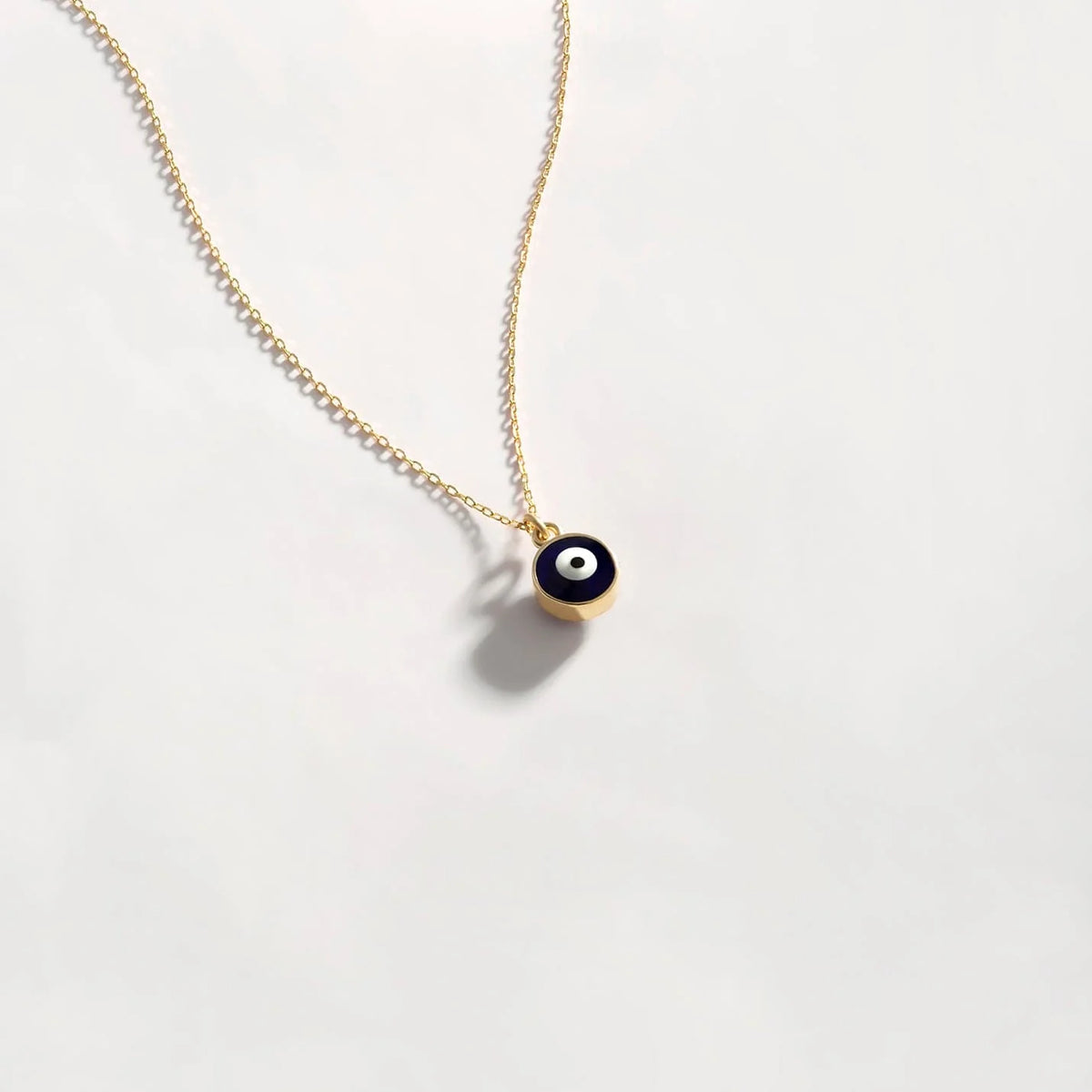 Silver evil eye pendant necklace with blue and white eye design, hanging from a delicate chain, by MUHVA STORE.