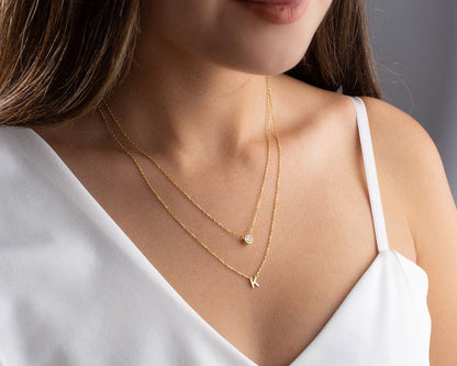 Gold diamond initial layer necklace with a delicate chain and a sparkling initial pendant, showcasing elegant jewelry design.