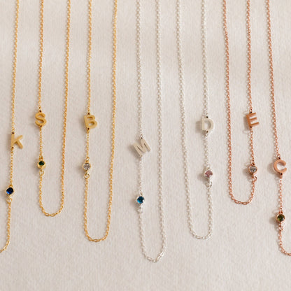 Silver sideways initial birthstone necklace with a colorful gemstone pendant, elegant jewelry piece from MUHVA STORE.
