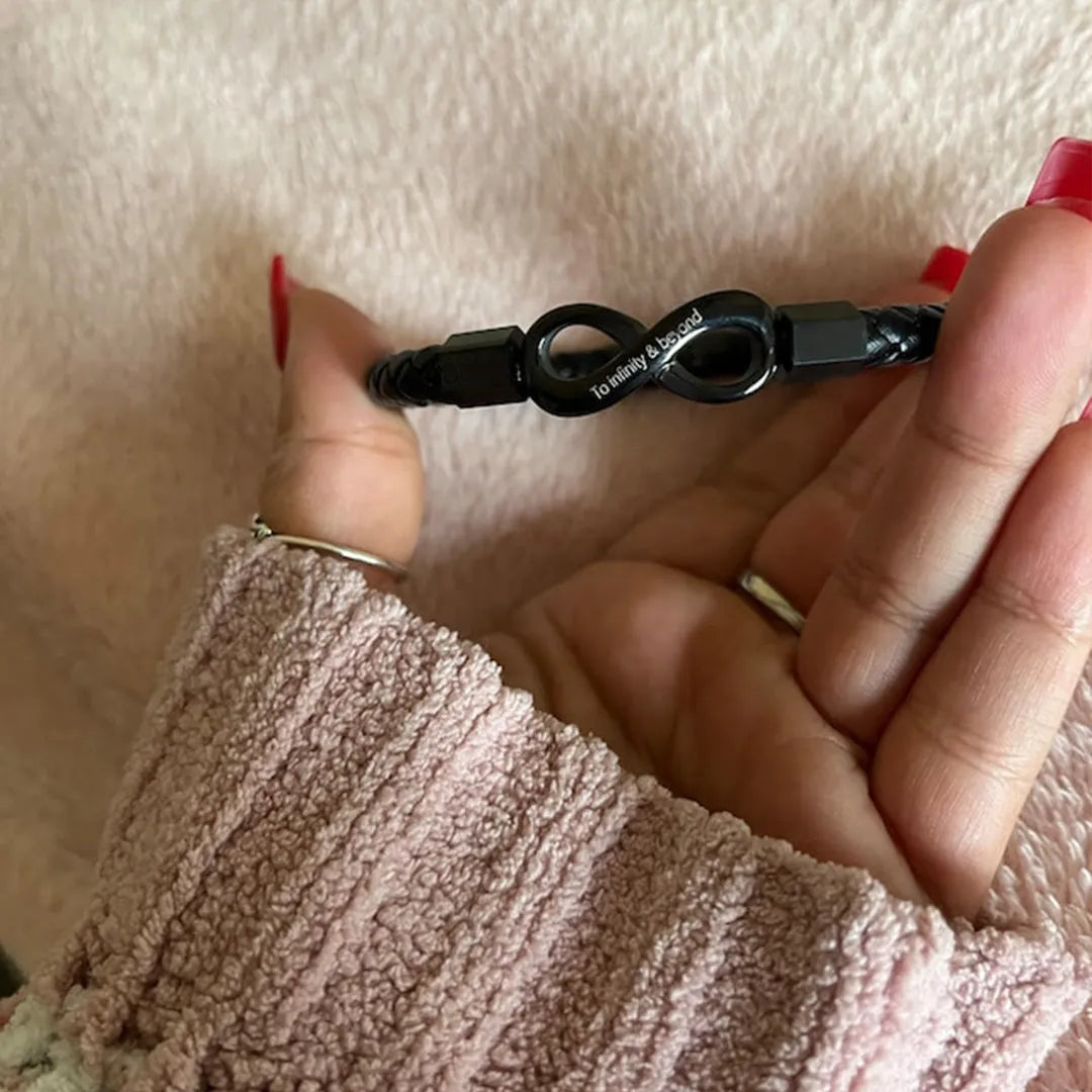 Personalized leather bracelet for husband with two engraved names and infinity symbol, featuring black leather band and silver clasp.