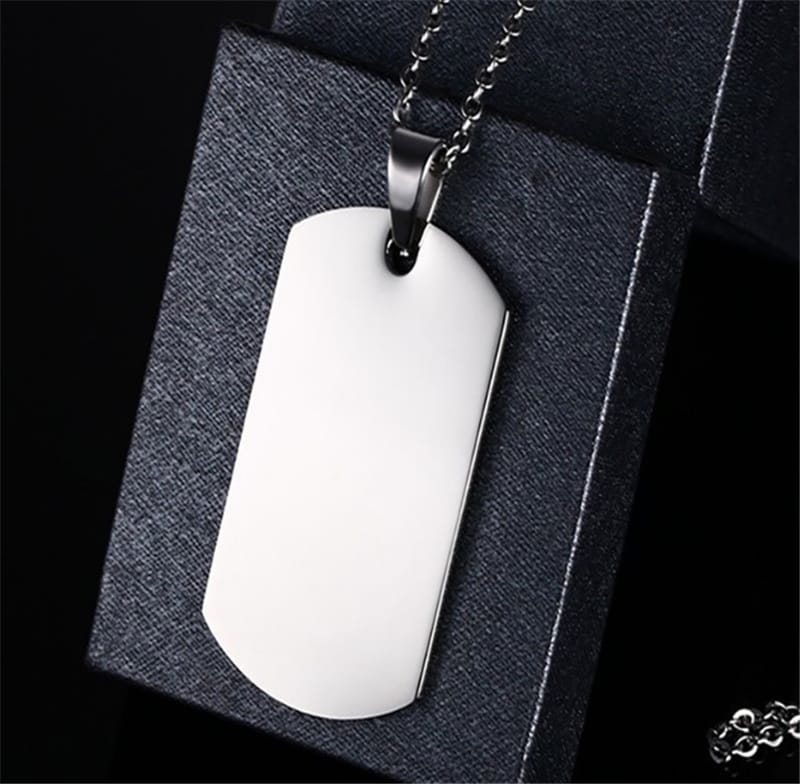 Two silver customized pendants with intricate designs, featuring personalized engravings, on a plain background.